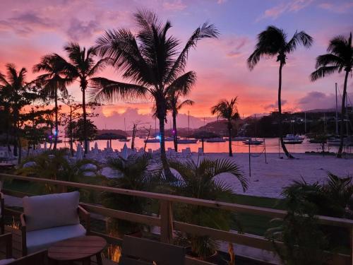 a view of a beach with palm trees and a sunset at Blue Lagoon Hotel and Marina Ltd in Kingstown