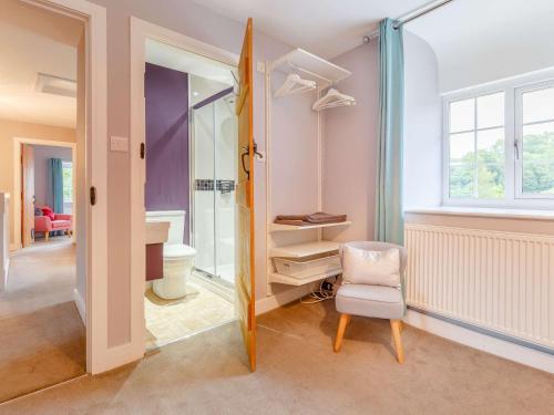 a bathroom with a toilet and a chair and a window at 4 Bed in Umberleigh 50154 in Burrington