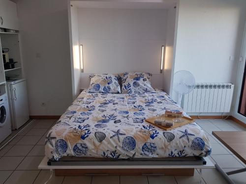 a bedroom with a bed with a blue and white comforter at Studio dans résidence de standing avec parking et sa terrasse vue mer in Bidart