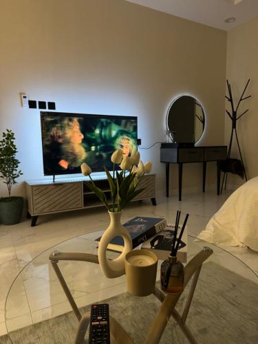 uma sala de estar com televisão e um vaso com flores em استديو مميز بدخول ذاتي em Riyadh