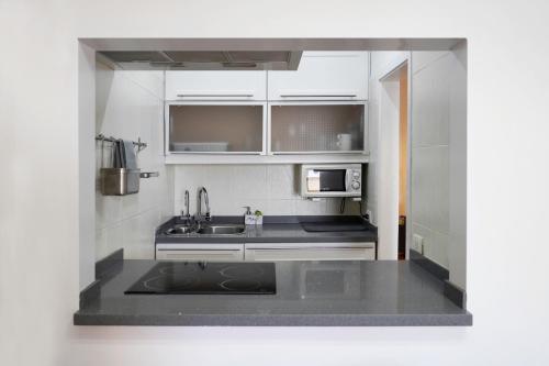 a small kitchen with a sink and a microwave at Playa Chica Beachfront Apartment in Santa Cruz de Tenerife