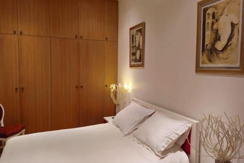 - une chambre avec un lit blanc et des placards en bois dans l'établissement Very Chic Flat Paris VI, à Paris