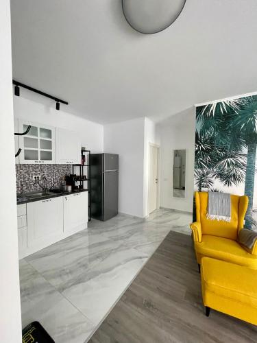 a living room with a yellow couch and a kitchen at Mathias Airport Residences & Therme-Self Check-in in Otopeni
