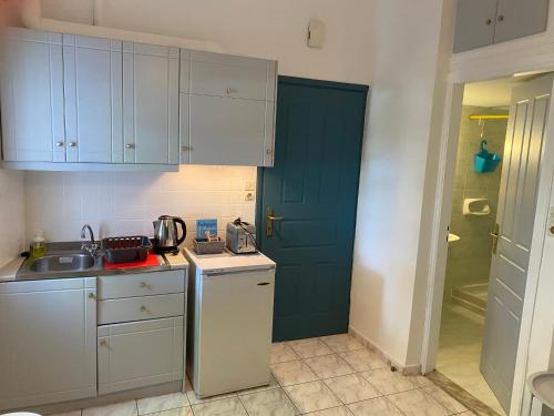eine Küche mit einem Waschbecken und einer blauen Tür in der Unterkunft Mitato Studios in Myrtos