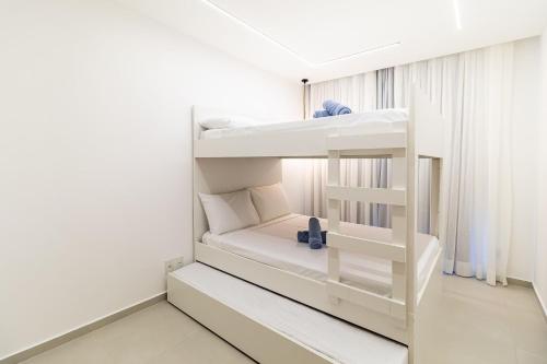 Ce lit superposé blanc se trouve dans une chambre blanche. dans l'établissement Elegância Tropical San Martin - Destino BSM 303 C, à Barra de São Miguel