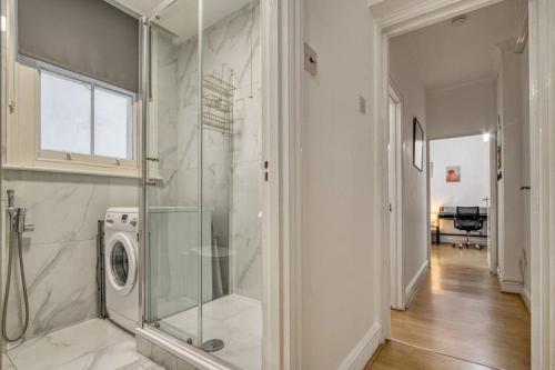 a bathroom with a shower and a washing machine at Cosy 2BR Retreat near Paddington Station in London