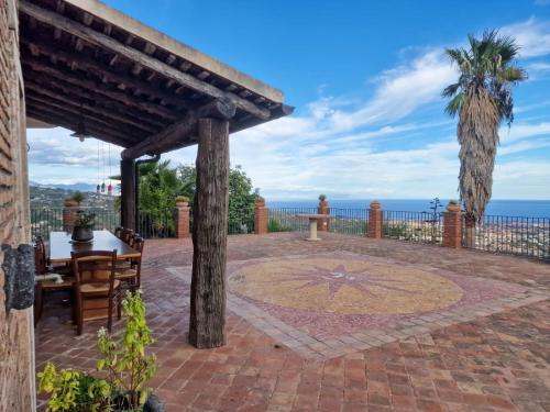 a patio with a table and chairs and the ocean at VILLA PANORAMICA DELL'ETNA in SantʼAlfio