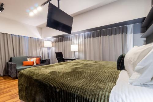a hotel room with a bed and a chair and a tv at Flat 1111 WCT Berrini Brooklin in Sao Paulo