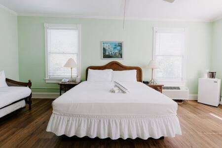 a bedroom with a white bed and two windows at King Suite at Curry Mansion with Heated Pool by Brightwild! in Key West