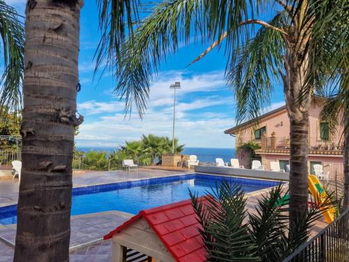 a resort pool with palm trees and a red bench at VILLA PANORAMICA DELL'ETNA in SantʼAlfio