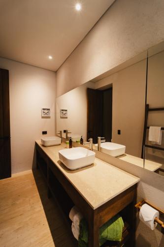 a bathroom with two sinks and a large mirror at Naio Hotel y Villas By OxoHotel in Palomino