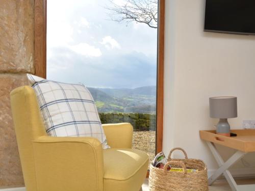 a yellow chair sitting in a room with a window at 2 Bed in Tansley 78219 in Tansley