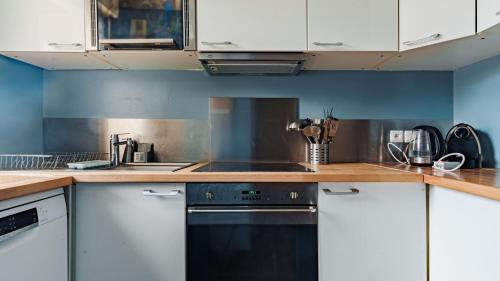 une cuisine avec des armoires blanches et une cuisinière dans l'établissement Appartement Spacieux - Disney, à Chessy