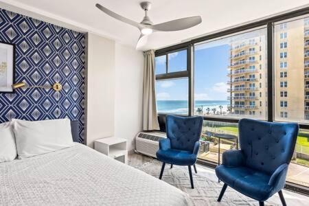 a bedroom with a bed and two blue chairs at Oceanside Duo - Double Room, Water Views, Pool & Beach Access, Free Parking in Daytona Beach