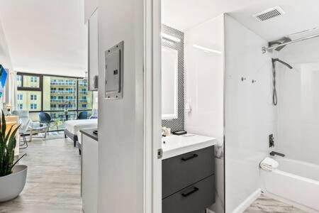 a white bathroom with a tub and a sink and a bath tub at Oceanside Duo - Double Room, Water Views, Pool & Beach Access, Free Parking in Daytona Beach