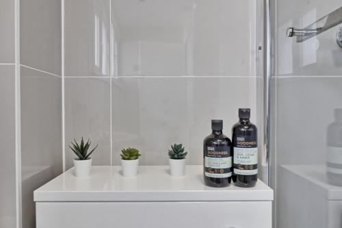 two bottles of wine sitting on a white counter in a bathroom at Newly Refurbished 3BR House Basildon, Garden, Netflix & Trisport Table in Nevendon