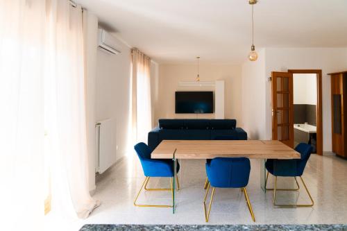 a living room with a wooden table and blue chairs at Gargano Home- Manfredi Homes & Villas in Manfredonia