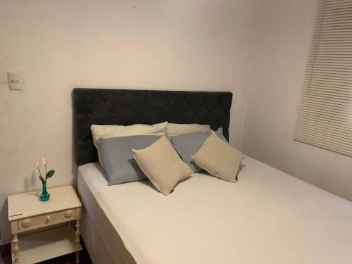 a bed with a black headboard and two pillows at Casa bem localizada e espaçosa no Butantã in São Paulo