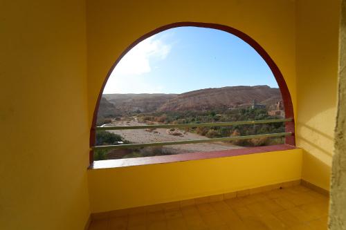 an arched window in a yellow room with a view at ACHAHOUD CHEz LA BELLE FIBULLE in Aït Fars