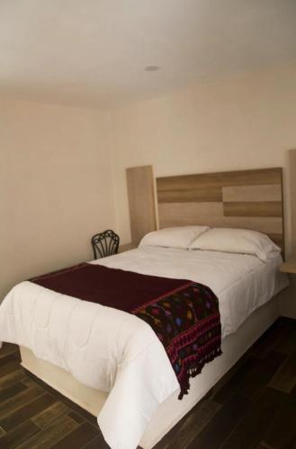 a bedroom with a large bed with a blanket on it at El ciruelo in Teziutlán