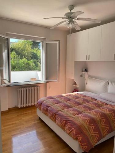 a bedroom with a bed with a ceiling fan and a window at Villetta familiare a Potenza Picena in Potenza Picena