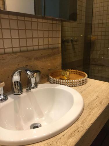 um balcão de casa de banho com um lavatório e um espelho em Condomínio Edificio Ilhabela Residence em Uberlândia