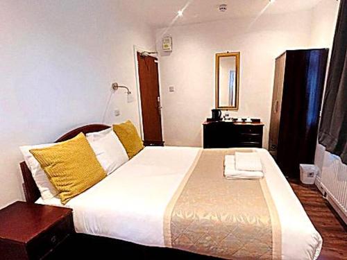 sypialnia z dużym łóżkiem z żółtymi poduszkami w obiekcie BA TRADERS w mieście Dagenham