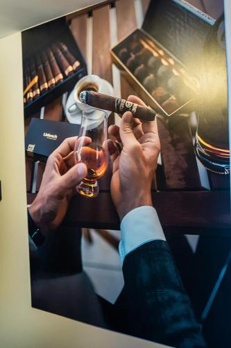 un homme en costume tenant un verre et un tuyau dans l'établissement Studio charmant, à Neuilly-sur-Marne