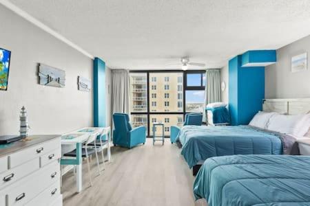 a hospital room with two beds and a table and chairs at Oceanside Inn 604 - Water Views, Beach Access Pool & Pool Bar in Daytona Beach