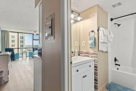 een witte badkamer met een wastafel, een bad en een bad bij Oceanside Inn 604 - Water Views, Beach Access Pool & Pool Bar in Daytona Beach