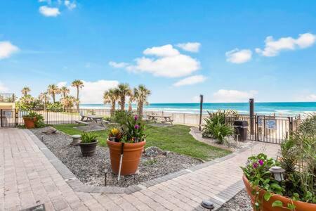a patio with plants and the beach in the background at Oceanside Inn 604 - Water Views, Beach Access Pool & Pool Bar in Daytona Beach