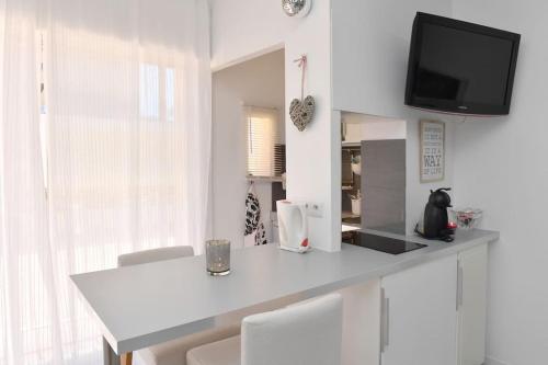 Il comprend une cuisine blanche avec un comptoir et une télévision murale. dans l'établissement Lovely studio with pool by the sea, à Roquebrune-Cap-Martin
