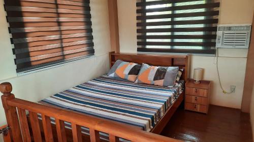 uma cama num quarto com duas almofadas e duas janelas em LS Resthouse with pool and garden em Calapan