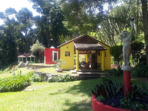 una pequeña casa amarilla con una estatua en el patio en Sítio Vila de Santa Barbara, en Caeté
