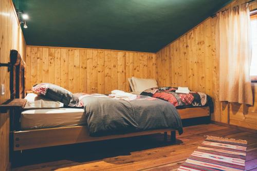 two beds in a room with wooden walls at Casa Franca trilocale in Argentera