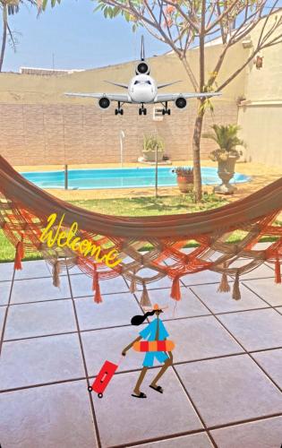 an airplane is flying over a hammock with a person with an umbrella at Aero Hostel in Londrina