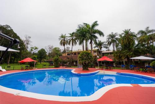 ein großer Pool in einem Resort mit Tischen und Sonnenschirmen in der Unterkunft HOTEL TROPICAL IGUAZU in Puerto Iguazú