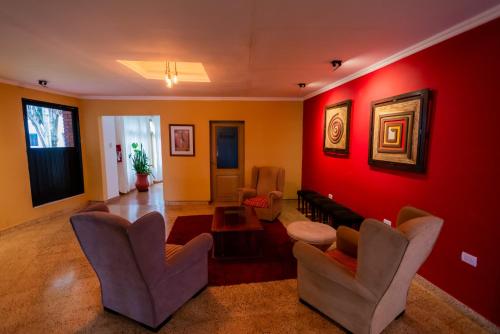 uma sala de estar com paredes e cadeiras vermelhas em HOTEL TROPICAL IGUAZU em Puerto Iguazú