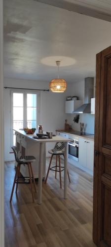 une cuisine avec une table blanche et deux chaises dans l'établissement Appartement lumineux centre, à Cessenon