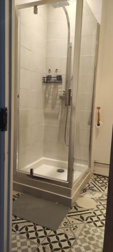 une douche avec une porte vitrée dans une salle de bain dans l'établissement Appartement lumineux centre, à Cessenon