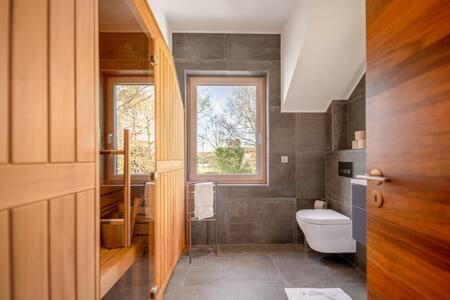 baño con aseo y ventana en Palatial Home - Sauna & Private Yard ID94, en Dippach