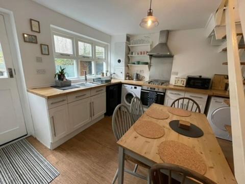 a kitchen with a wooden table and a table and chairs at Tewyn Cottage - Charming 2 bed getaway in the SW! in Hayle