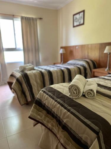 two beds in a hotel room with towels on them at Departamento en Colastine Norte in Colastiné
