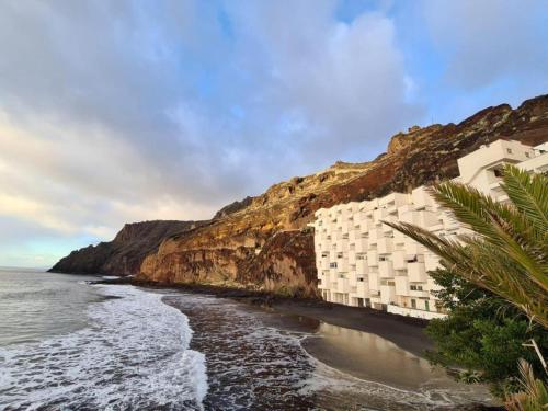 a hotel on a cliff next to the ocean at Playa Chica Beachfront Apartment in Santa Cruz de Tenerife