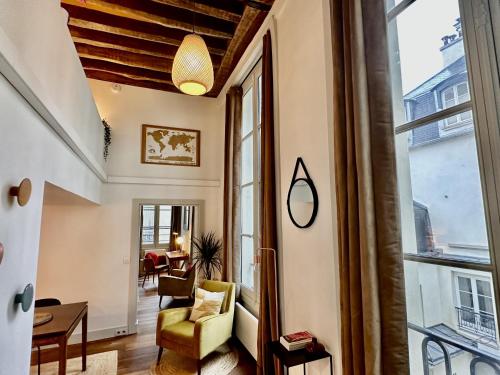 sala de estar con ventana grande y silla en Les appartements de l'atelier Paris 3, en París