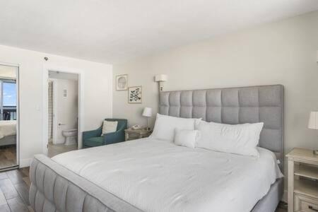 a bedroom with a large white bed and a blue chair at The Scallop by Brightwild-Beachfront Condo in Destin