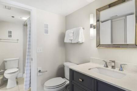 a bathroom with a toilet and a sink and a mirror at The Scallop by Brightwild-Beachfront Condo in Destin