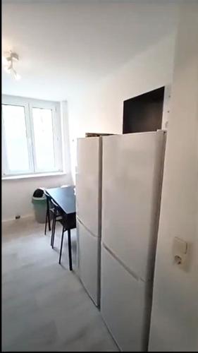 een witte koelkast in een keuken met een tafel bij Apartkeep Plauen 25 in Plauen
