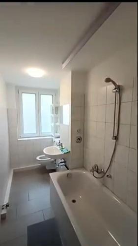 een witte badkamer met een bad en een wastafel bij Apartkeep Plauen 25 in Plauen