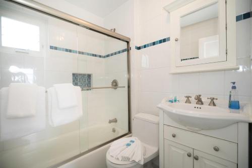 a white bathroom with a shower and a sink at The Montauk Soundview in Montauk
